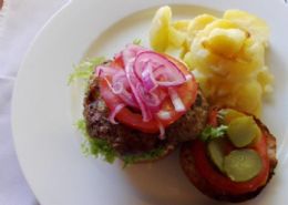 A beef patty (gluten free) on gluten free toast, with cheese, mustard, tomato sauce, fresh tomato, gherkin, red onion and potato bake.